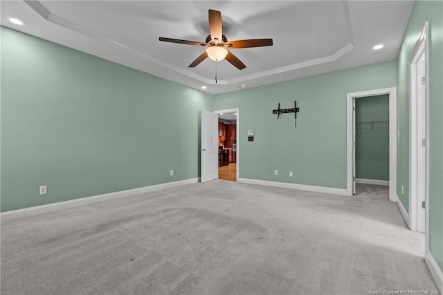 unfurnished bedroom featuring a raised ceiling, recessed lighting, baseboards, carpet, and crown molding