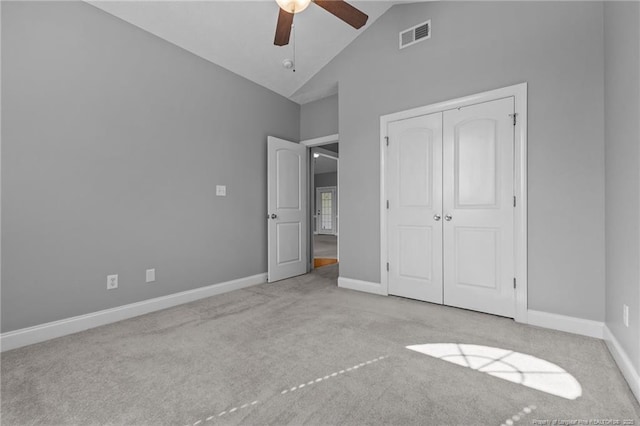unfurnished bedroom featuring carpet, a closet, a ceiling fan, baseboards, and high vaulted ceiling