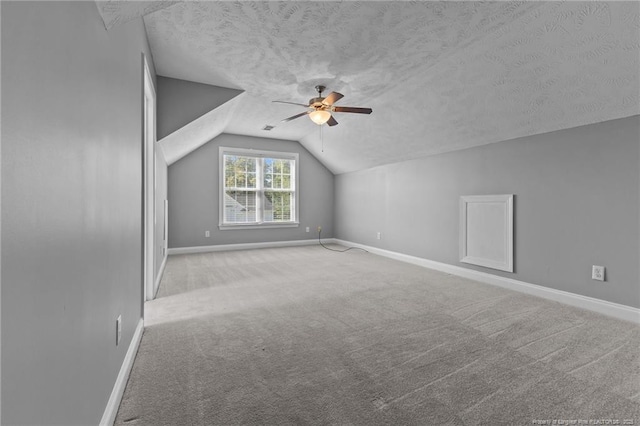 additional living space featuring lofted ceiling, ceiling fan, a textured ceiling, baseboards, and carpet floors