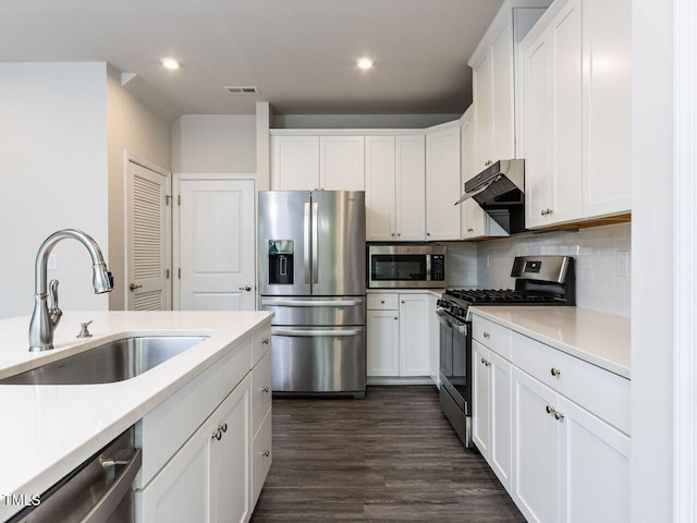 kitchen with stainless steel appliances, under cabinet range hood, a sink, recessed lighting, and white cabinetry