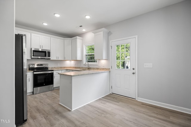 208 W Holt St, Burlington, NC 27217 - kitchen featuring appliances with stainless steel finishes, a peninsula, white cabinets, light wood-style flooring, and light stone countertops