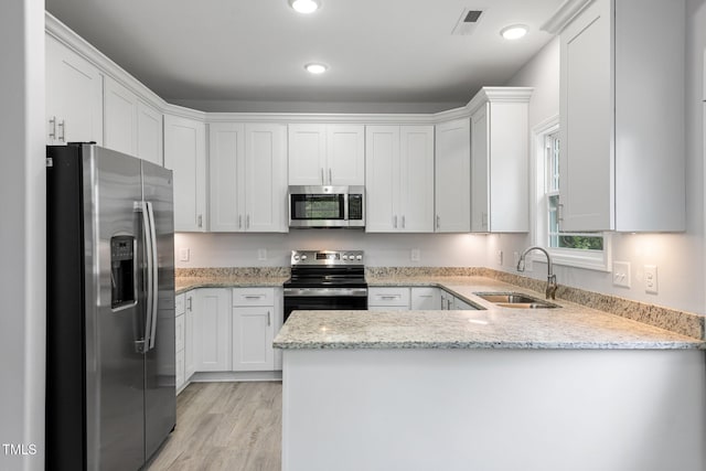 208 W Holt St, Burlington, NC 27217 - kitchen with stainless steel appliances, a sink, a peninsula, white cabinets, and light wood finished floors