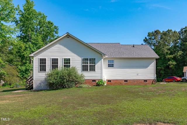 rear view of house featuring crawl space, a lawn, and roof with shingles