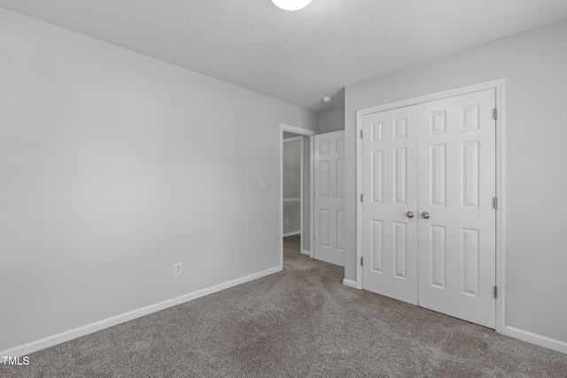 unfurnished bedroom featuring carpet floors, baseboards, a closet, and a textured ceiling