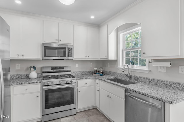 kitchen with appliances with stainless steel finishes, a sink, white cabinetry, light stone counters, and recessed lighting