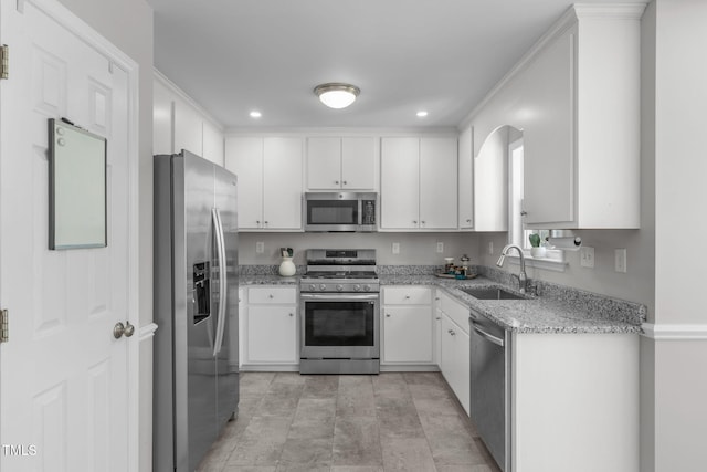 kitchen with appliances with stainless steel finishes, a sink, white cabinetry, light stone counters, and recessed lighting