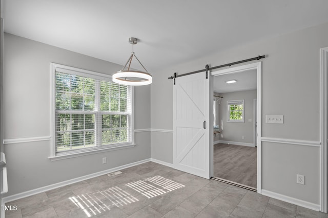 unfurnished dining area featuring a barn door and baseboards