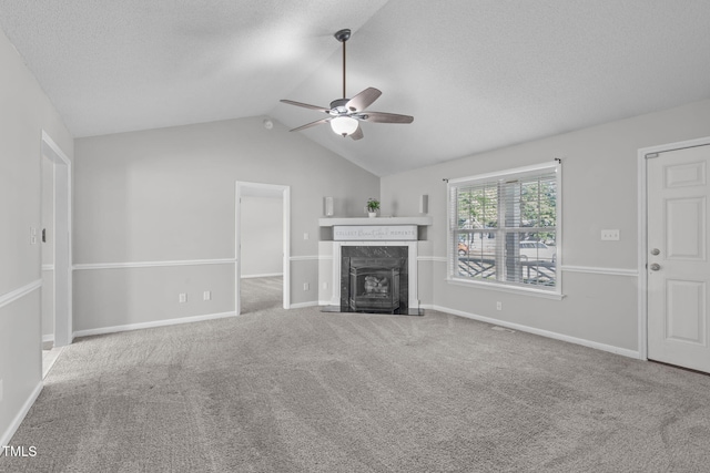 unfurnished living room featuring ceiling fan, carpet flooring, vaulted ceiling, a fireplace, and a textured ceiling