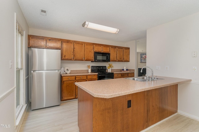 509 Darby Glen Ln, Durham, NC 27713 - kitchen featuring black appliances, a sink, brown cabinetry, light wood-style flooring, and a textured ceiling