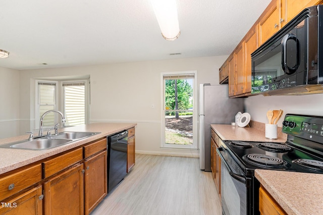 509 Darby Glen Ln, Durham, NC 27713 - kitchen with black appliances, a sink, brown cabinetry, and light wood finished floors