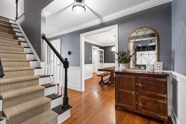 entryway featuring stairs, wainscoting, wood finished floors, and crown molding