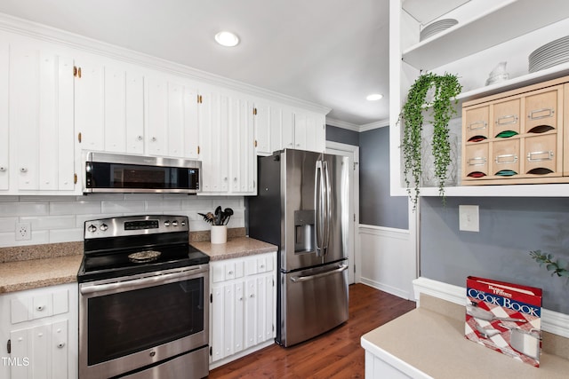kitchen with appliances with stainless steel finishes, dark wood finished floors, white cabinetry, light countertops, and crown molding