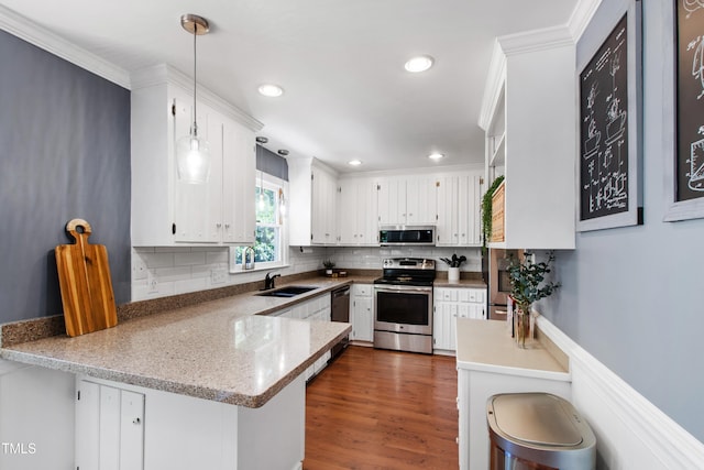 kitchen with appliances with stainless steel finishes, a sink, white cabinets, a peninsula, and decorative backsplash