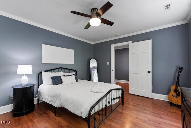 bedroom featuring crown molding, wood finished floors, baseboards, a ceiling fan, and arched walkways