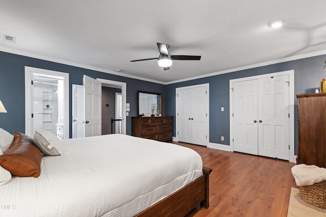 bedroom featuring two closets, wood finished floors, ornamental molding, a ceiling fan, and baseboards