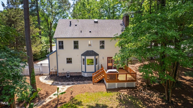 rear view of house with a deck, a chimney, fence, and a shingled roof