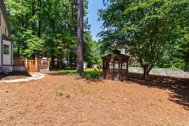 view of yard with a gazebo, a deck, a storage unit, an outdoor structure, and fence