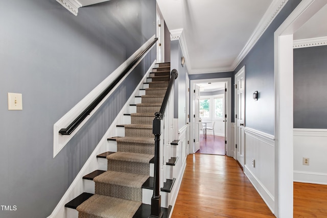 stairway featuring wood finished floors and ornamental molding