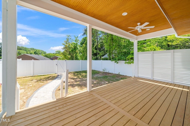wooden deck featuring a fenced backyard, a gate, ceiling fan, and view of scattered trees