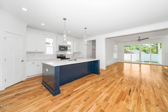 kitchen with stainless steel appliances, a sink, light wood-style flooring, light countertops, and plenty of natural light