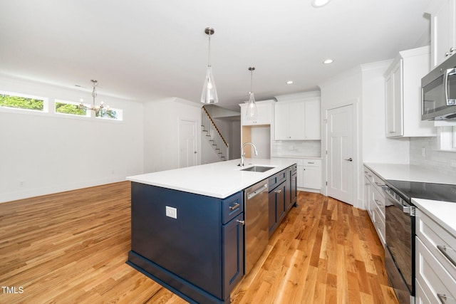 kitchen featuring appliances with stainless steel finishes, a sink, blue cabinetry, tasteful backsplash, and white cabinetry