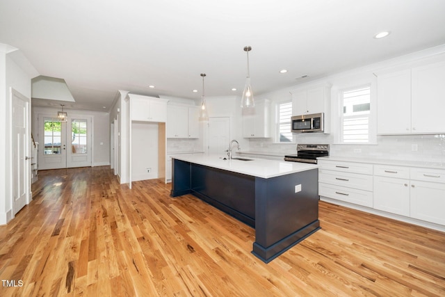 kitchen featuring stainless steel appliances, a sink, white cabinetry, light countertops, and decorative backsplash