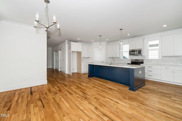 kitchen featuring appliances with stainless steel finishes, a sink, a chandelier, white cabinetry, and light wood-style flooring