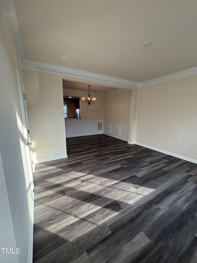 spare room with ornamental molding, a chandelier, dark wood finished floors, and baseboards