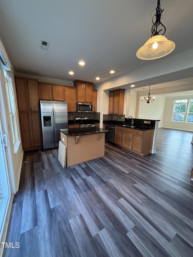kitchen featuring stainless steel appliances, a chandelier, a center island, dark wood-style flooring, and a sink