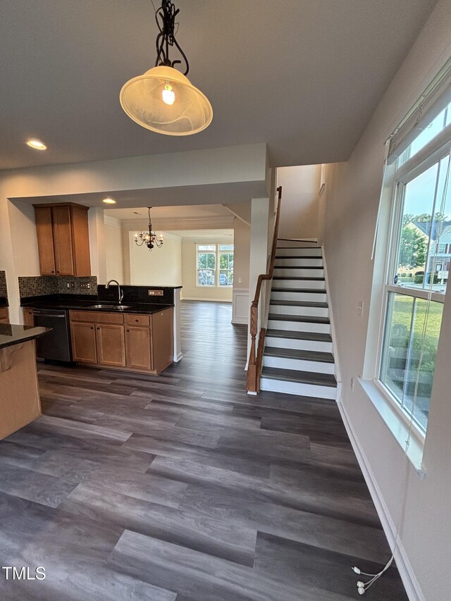 kitchen with dishwasher, dark countertops, a sink, a chandelier, and decorative light fixtures