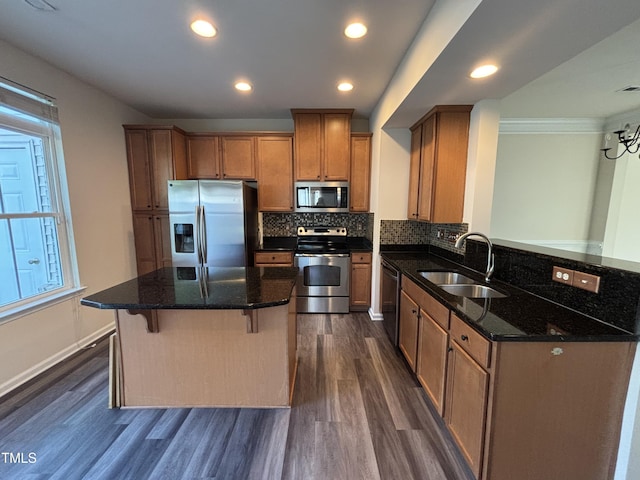 kitchen featuring appliances with stainless steel finishes, a sink, dark wood-type flooring, brown cabinetry, and backsplash