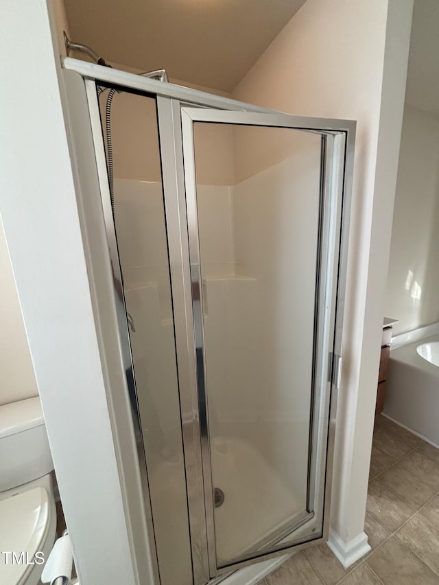 full bathroom with a stall shower, tile patterned flooring, and toilet