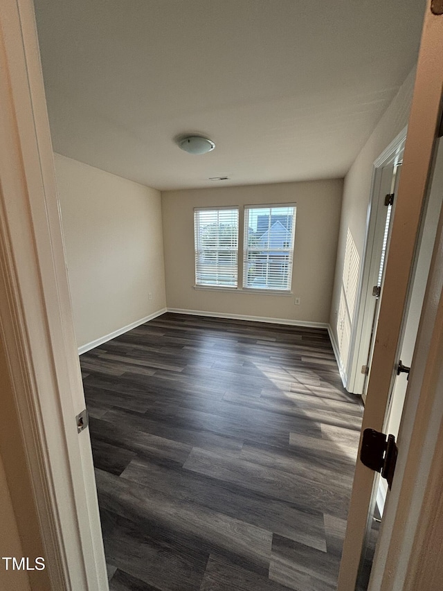 unfurnished room with dark wood-type flooring and baseboards