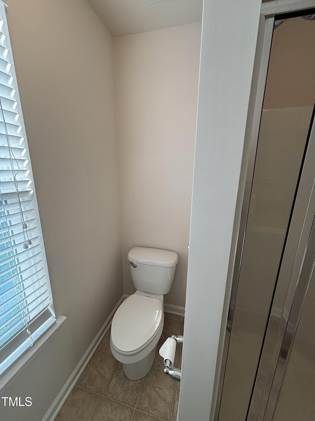 bathroom featuring toilet, tile patterned flooring, and baseboards