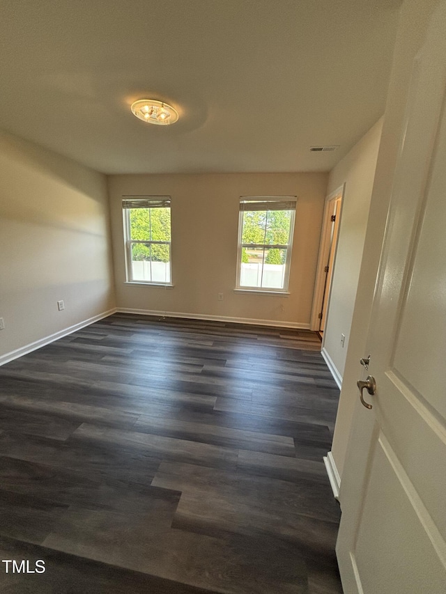 unfurnished room with plenty of natural light, dark wood finished floors, and baseboards