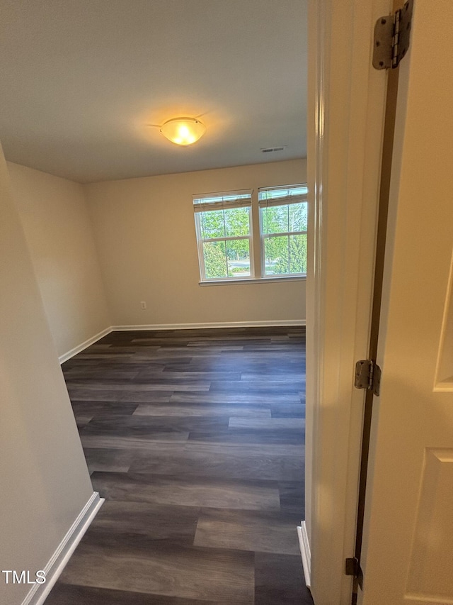 unfurnished room featuring dark wood-style floors and baseboards