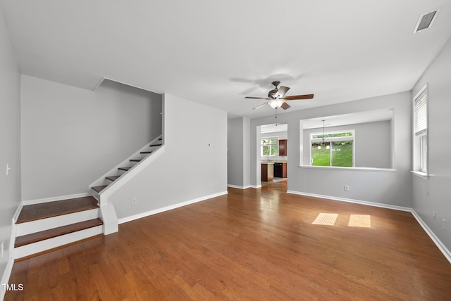 unfurnished living room featuring ceiling fan, stairway, wood finished floors, and baseboards