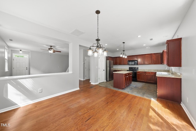 kitchen featuring black appliances, a center island, baseboards, open floor plan, and recessed lighting