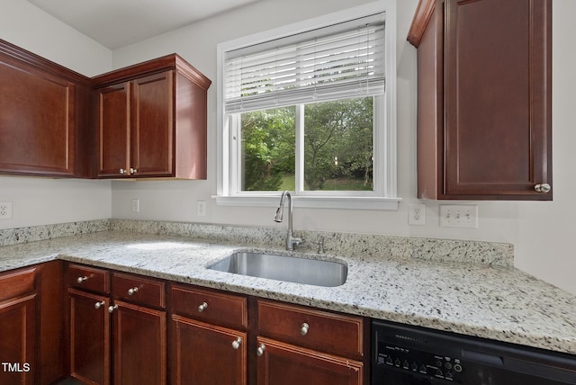 kitchen with a sink, dishwasher, and light stone counters