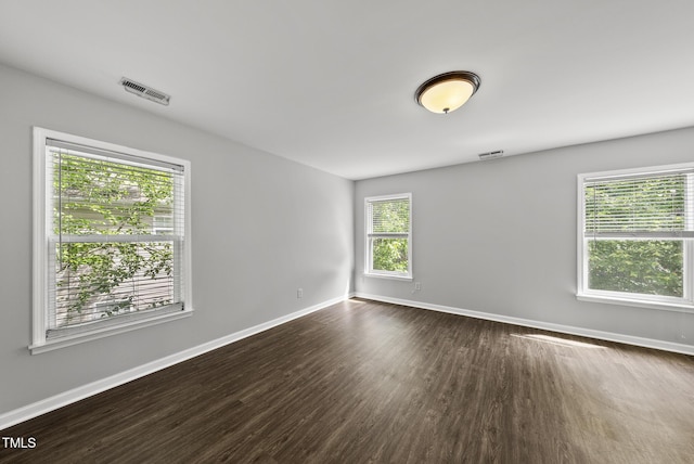 spare room with baseboards and dark wood finished floors