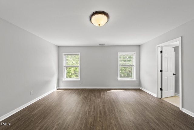 empty room featuring healthy amount of natural light, wood finished floors, and baseboards