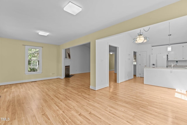 4705 Forest Highland Dr, Raleigh, NC 27604 - unfurnished living room featuring light wood finished floors, a fireplace with flush hearth, and baseboards