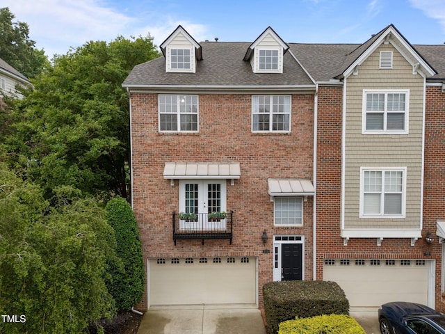 view of front facade featuring an attached garage, brick siding, driveway, a shingled roof, and french doors