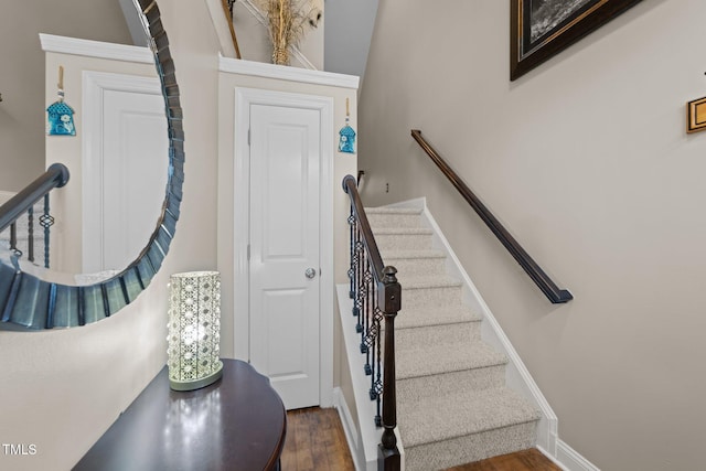 staircase featuring wood finished floors and baseboards