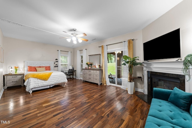 bedroom featuring wood finished floors, baseboards, access to exterior, a glass covered fireplace, and a ceiling fan