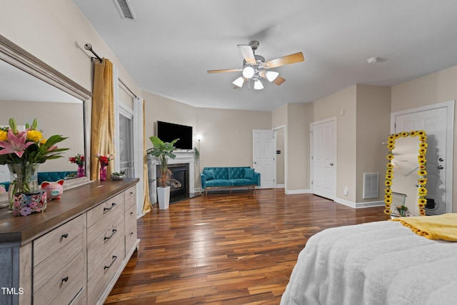 bedroom with dark wood-style flooring, baseboards, a fireplace with flush hearth, and ceiling fan