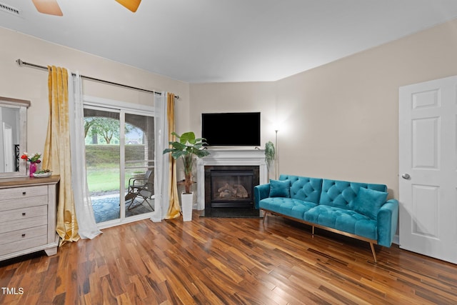 living room with wood finished floors, ceiling fan, and a glass covered fireplace