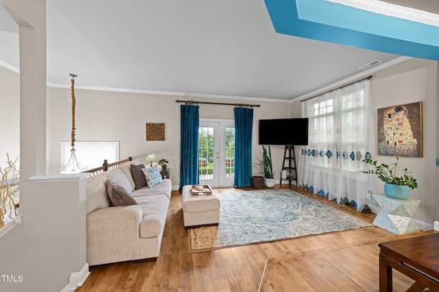 living room with wood finished floors, ornamental molding, and baseboards