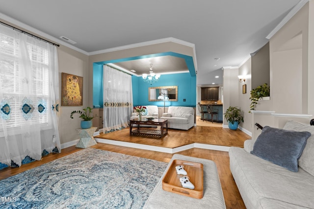 living area with a chandelier, wood finished floors, healthy amount of natural light, crown molding, and recessed lighting