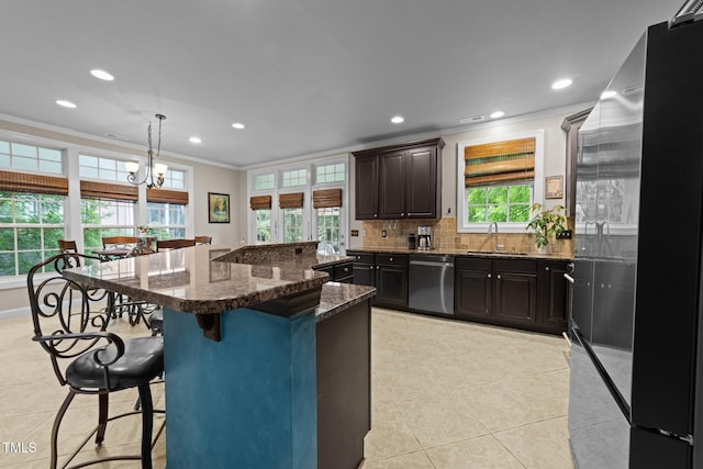 kitchen featuring stainless steel appliances, a sink, crown molding, a kitchen breakfast bar, and backsplash